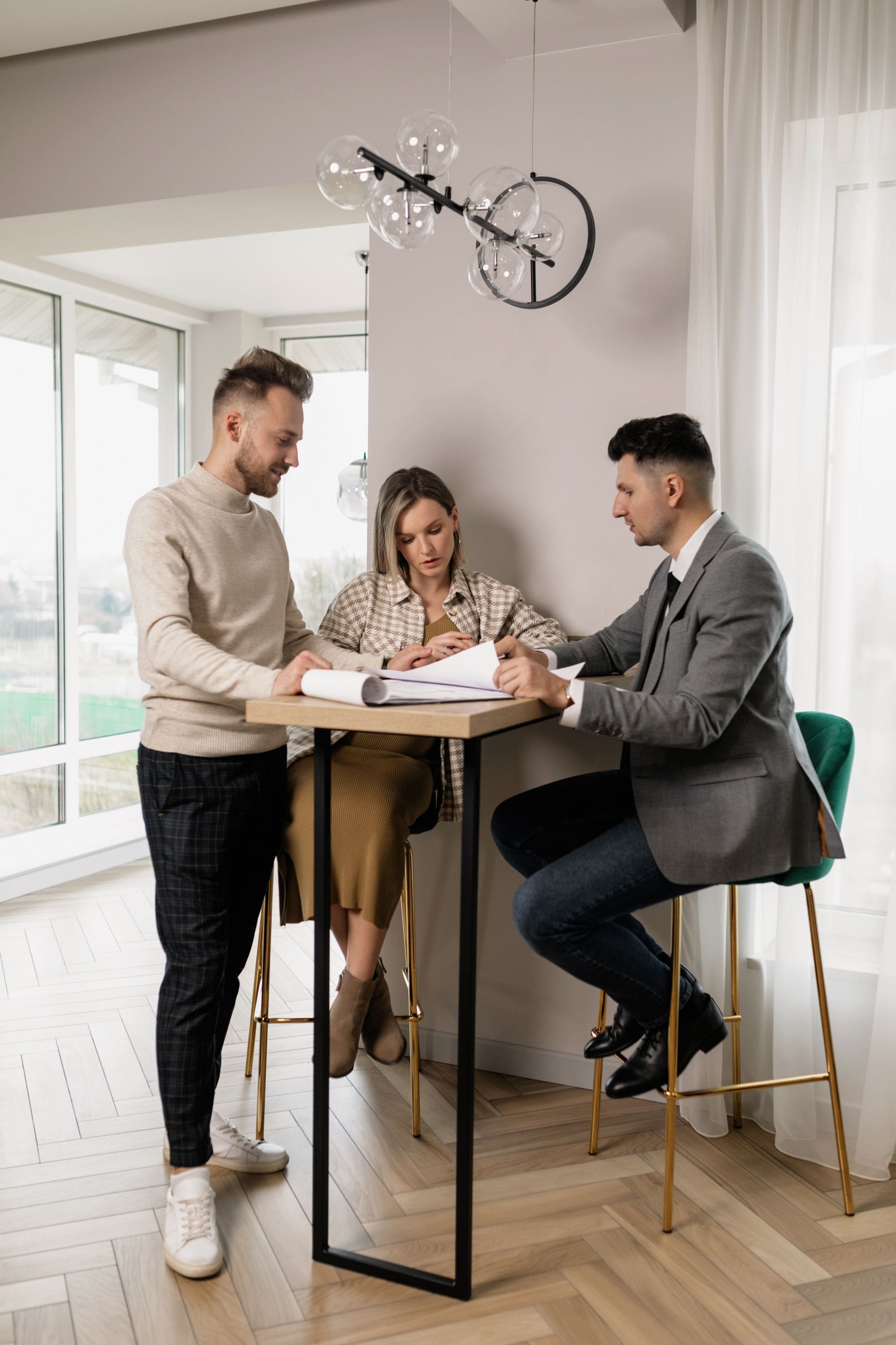 A couple reviewing documents with their agent in a bright, modern room