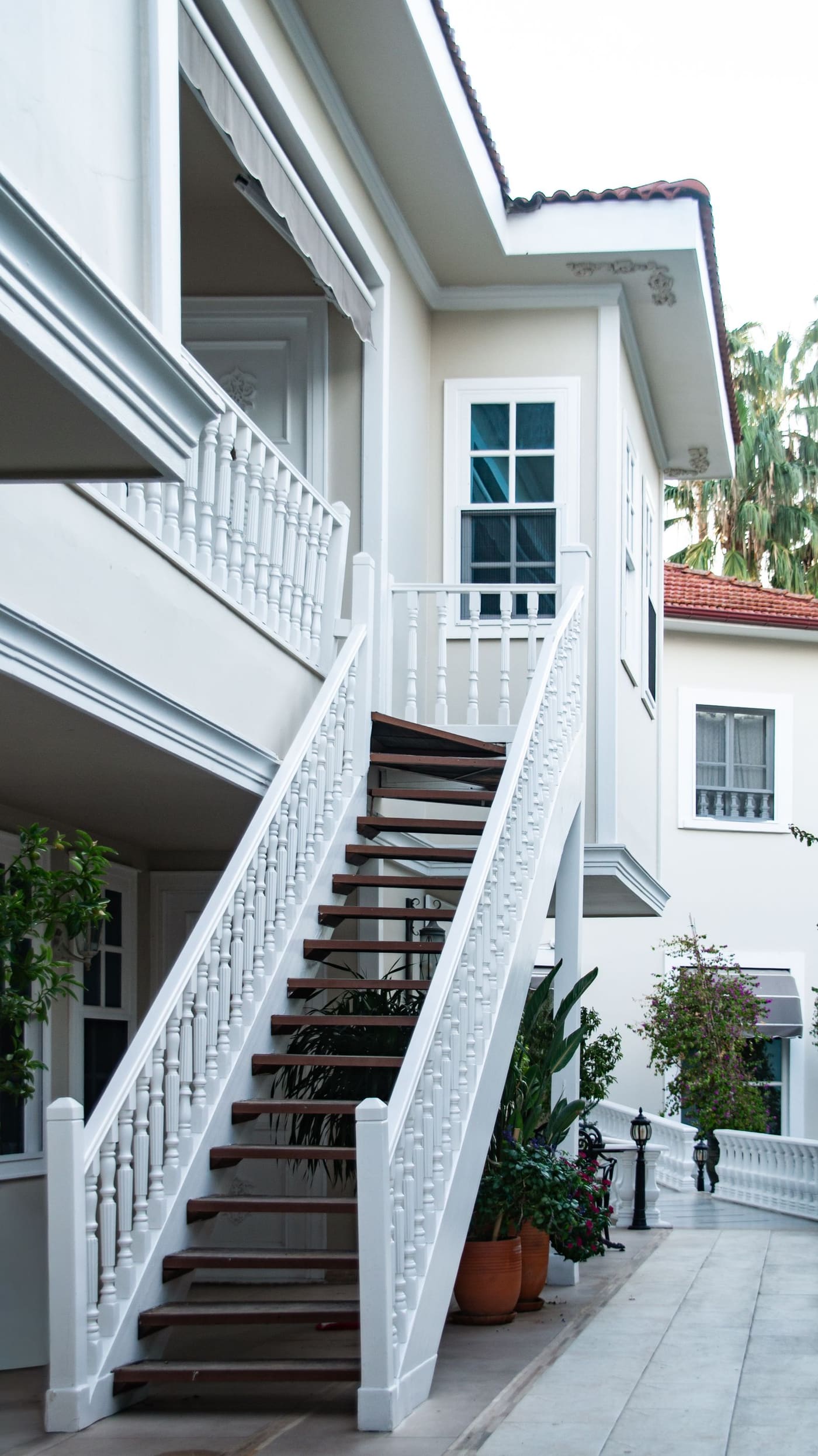 A white exterior staircase climbing beside lush planting