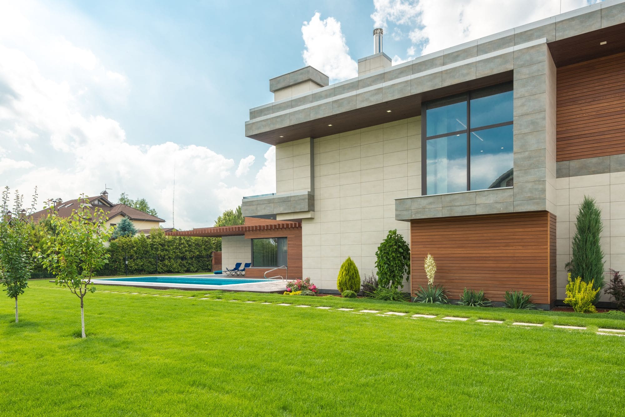 A contemporary home with a pool beyond a broad, manicured lawn