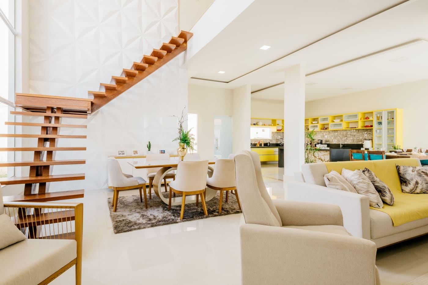 A bright open-plan living and dining space with a floating timber staircase