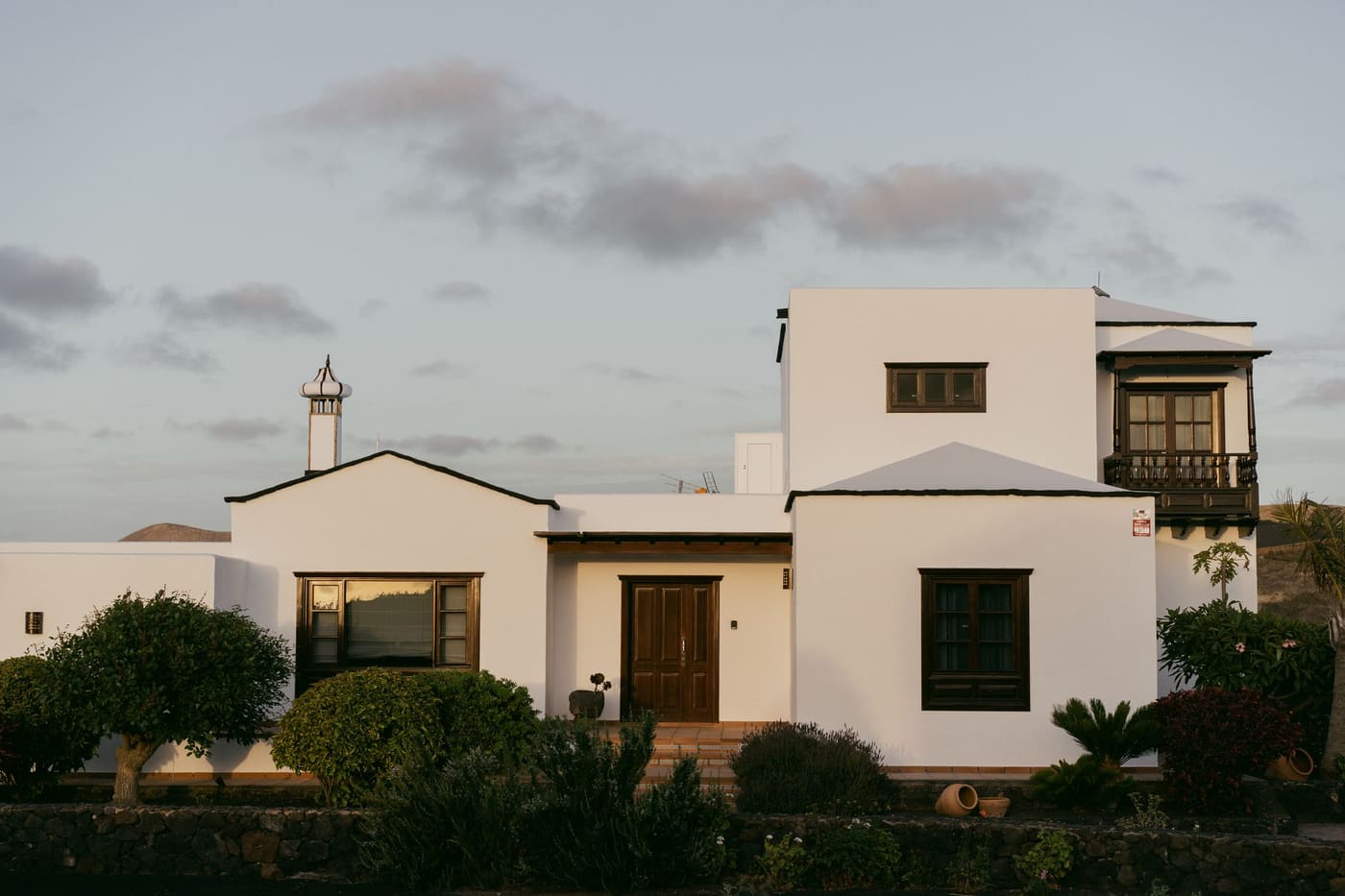 A white villa framed by tall trees in the evening light
